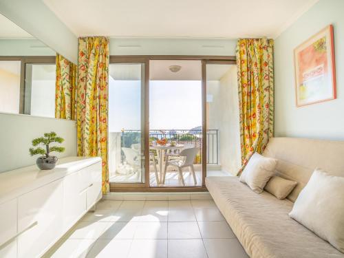 ein Wohnzimmer mit einem Sofa und einem Balkon in der Unterkunft Apartment L'Ange Gardien by Interhome in Beaulieu-sur-Mer