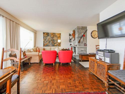 Apartment Center by Interhome في زيرمات: غرفة معيشة مع كراسي حمراء وتلفزيون بشاشة مسطحة