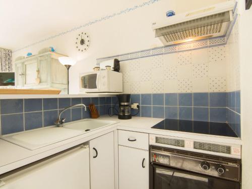 une cuisine avec des placards blancs et du carrelage bleu dans l'établissement Studio Ulysse Plage-12 by Interhome, à La Grande Motte