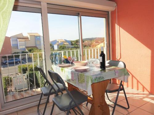 a table with chairs and a bottle of wine on a balcony at Apartment Les Balcons de la Méditerranée-18 by Interhome in Narbonne-Plage