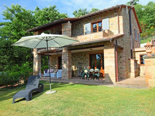 a stone house with an umbrella in the yard at Villa Oleandra sul Lago by Interhome in San Feliciano
