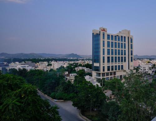 ein hohes Gebäude mit einem Fluss vor einer Stadt in der Unterkunft Pride Hotel Udaipur in Udaipur
