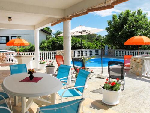 een terras met een tafel en stoelen en een zwembad bij Apartment Mira-2 by Interhome in Pinezici