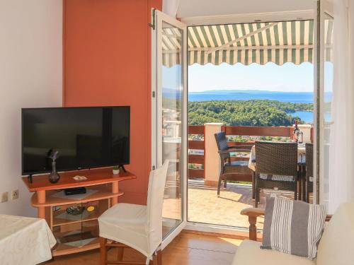 ein Wohnzimmer mit einem TV und einer Glasschiebetür in der Unterkunft Apartment Andrija - RAB313 by Interhome in Rab