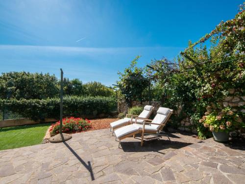 two white chairs sitting on a stone patio at Apartment Jasna-5 by Interhome in Pinezici