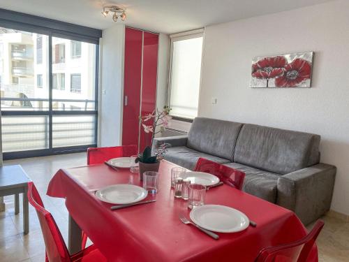 a living room with a red table and a couch at Apartment Les Rivages de Rochelongue-3 by Interhome in Cap d'Agde