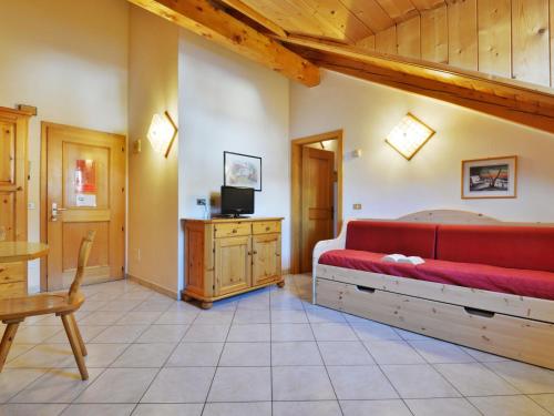 a bedroom with a red couch and a tv at Apartment Villa Placidia Apt 34 by Interhome in Campitello di Fassa