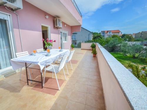 une table et des chaises sur le balcon d'une maison rose dans l'établissement Apartment Šime by Interhome, à Brodarica