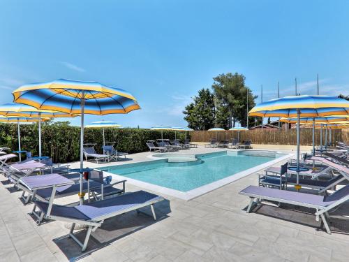 - une piscine avec des parasols et des chaises bleus et jaunes dans l'établissement Apartment Riviera 2 by Interhome, à Marina di Cecina