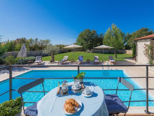 a table with a plate of food next to a pool at Villa Histria 1 by Interhome in Čabrunići