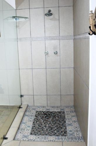 a shower with a black and white tile floor at Kleinzee Oceanfront Guesthouse in Gansbaai