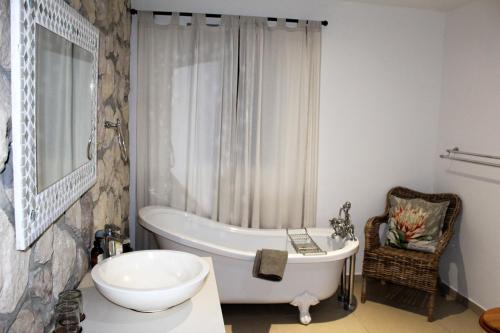 a bathroom with a bath tub and a sink at Kleinzee Oceanfront Guesthouse in Gansbaai