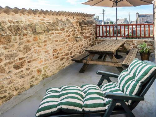a patio with a wooden table and chairs and an umbrella at Holiday Home Manoir des Halles by Interhome in Plouescat