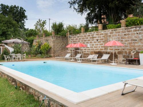 - une piscine avec des chaises et des parasols à côté d'un mur de briques dans l'établissement Holiday Home Casale Ai Noccioli - LVC165 by Interhome, à Corchiano