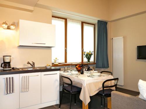 a kitchen with a table with chairs and a white kitchen at Apartment Bilocale by Interhome in Olgiasca