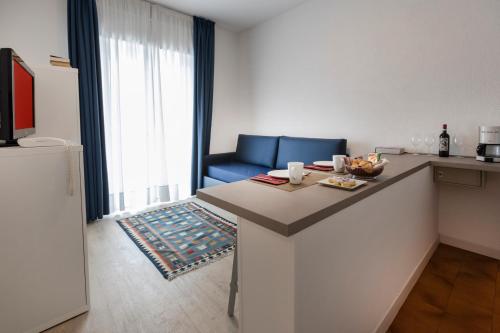 a kitchen with a counter with a blue couch in a room at Hotel Roma Aparthotel in Malcesine