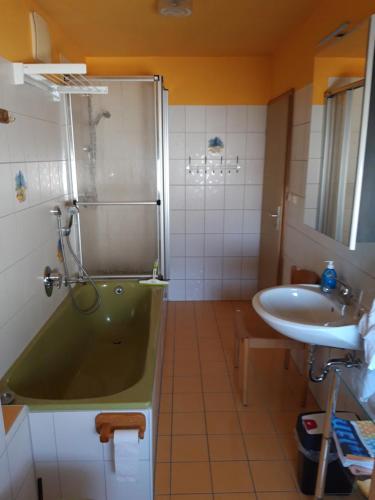 a bathroom with a green tub and a sink at Ferienwohnung im Seidlerhof mit Balkon und Garten in Röhrnbach