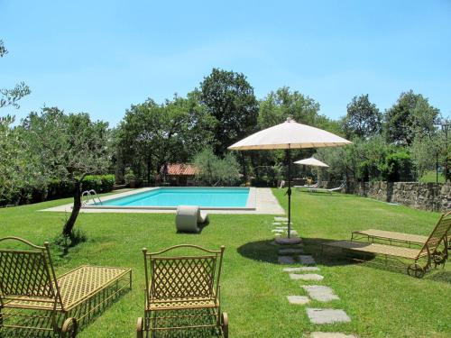 a yard with two chairs and an umbrella and a pool at Apartment La Fornace-3 by Interhome in Il Molinaccio