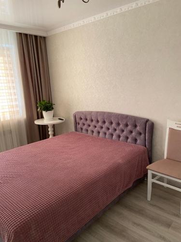 a bedroom with a purple bed and a chair at Квартира студия in Izmail