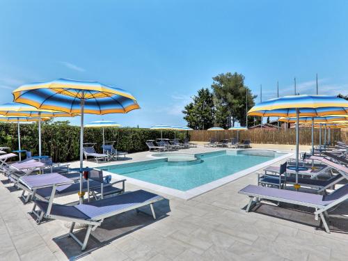 a pool with blue and yellow umbrellas and chairs at Apartment Riviera 8 by Interhome in Marina di Cecina