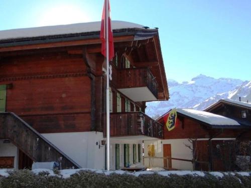 a building with a flag in the snow at Apartment Teleboy by Interhome in Lenk