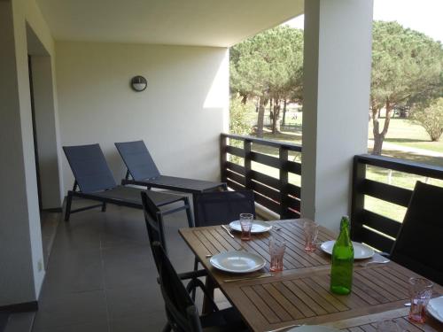 - une table avec des chaises et une bouteille de vin sur le balcon dans l'établissement Apartment Le Golf Clair-14 by Interhome, à Saint-Cyprien