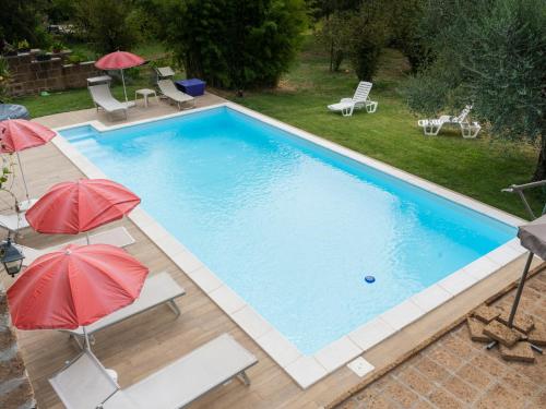 a swimming pool with two umbrellas and chairs at Apartment Casale Ai Noccioli-2 by Interhome in Corchiano