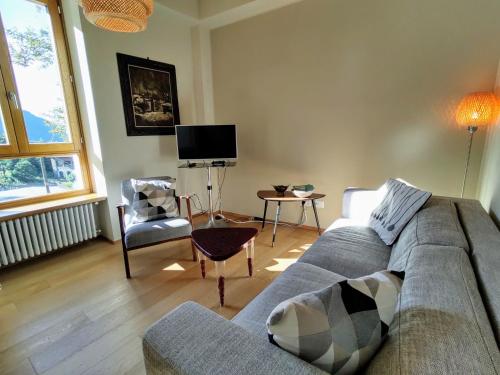 ein Wohnzimmer mit einem Sofa und einem TV in der Unterkunft Apartment Trilocale by Interhome in Olgiasca