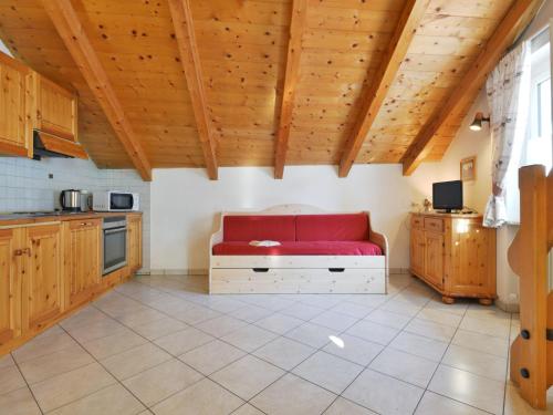 un divano rosso in una cucina con soffitti in legno di Apartment Villa Placidia Apt 33 by Interhome a Campitello di Fassa