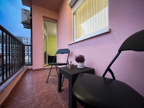 un balcone con due sedie e un tavolo e una parete rosa di Apartman Central a Bijeljina