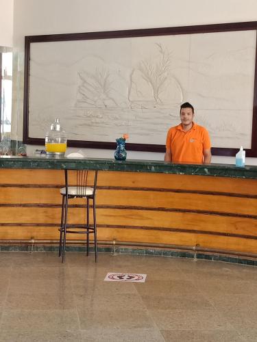 a man standing behind a bar in a room at Green Sudr Resort in Ras Sedr