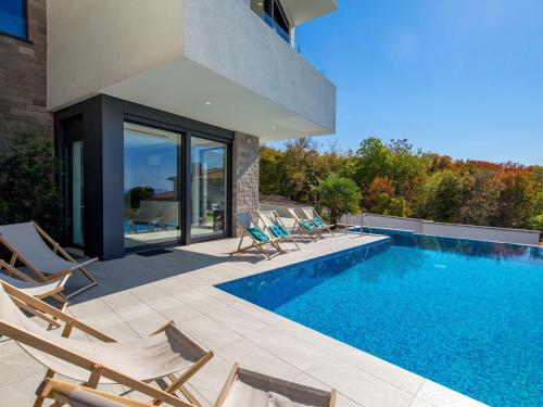 Villa Albi by Interhome في كوسترينا: مسبح مع كراسي جلوس بجانب بيت