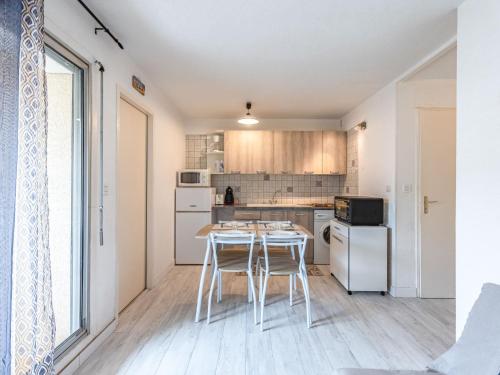 une cuisine avec des appareils électroménagers blancs et une table avec des tabourets dans l'établissement Apartment Jean Bart I by Interhome, au Cap d'Agde