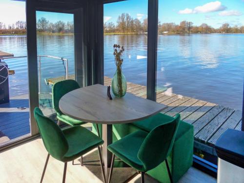 a table with chairs and a vase of flowers on a dock at Holiday Home De Meerparel-1 by Interhome in Uitgeest