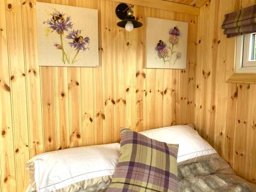a bedroom with wooden walls with a bed and two pictures at Remarkable Shepherds Hut in a Beautiful Location in Perth