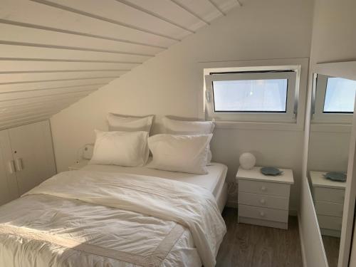 a white bedroom with a bed and a window at Lovely 2-bedroom apartment- Comporta in Carvalhal