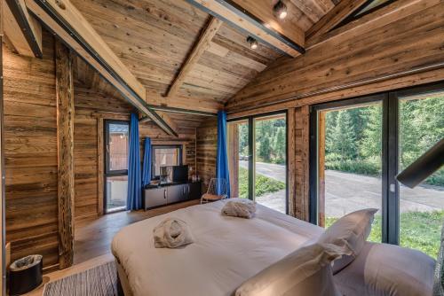 een slaapkamer in een blokhut met een bed en ramen bij Chalet Carte Blanche Monts in Tignes