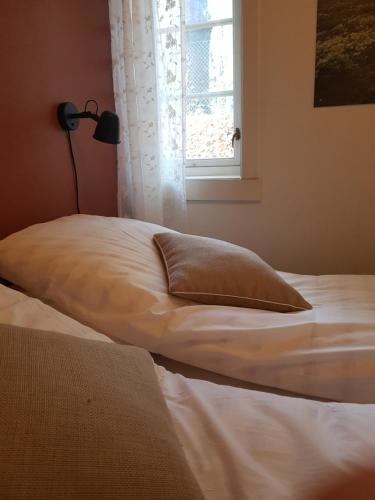 a bed with a pillow on it next to a window at Pilegrimsgården Hotell og Gjestegård in Trondheim