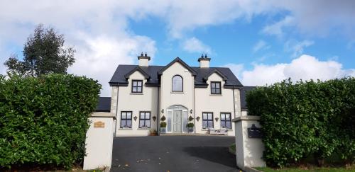 a large white house with a gate and bushes at Relax at Safe Haven in Carlingford