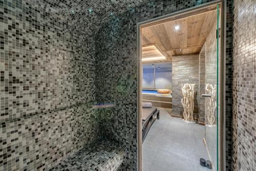 La salle de bains est pourvue d'une douche et de murs carrelés. dans l'établissement Chalet Carte Blanche Merveilles, à Tignes