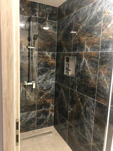 a bathroom with a shower with black marble tiles at Apartament Telkom 1 in Milówka