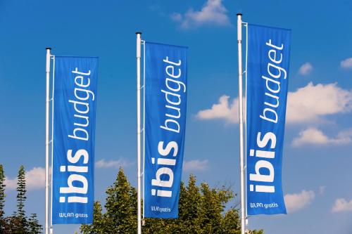 three blue flags with the wordovation on them at Ibis budget München Airport Erding in Erding
