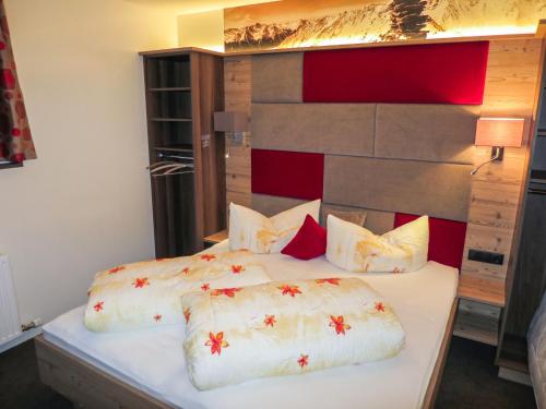 1 dormitorio con 1 cama grande con sábanas blancas y almohadas rojas en Apartment Alpenflora by Interhome, en Kappl