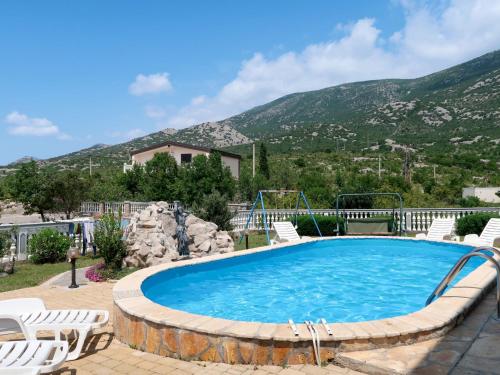 a swimming pool with chairs and a mountain at Holiday Home Golic - KBG302 by Interhome in Karlobag