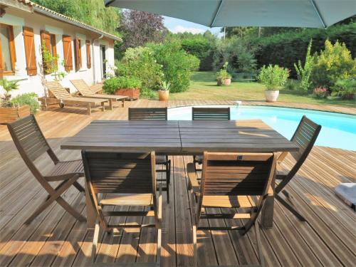 - une table en bois avec des chaises et un parasol à côté de la piscine dans l'établissement Holiday Home Taste Rebire by Interhome, à Vendays-Montalivet