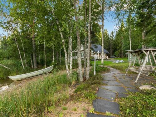 Holiday Home Torniniemi by Interhome في Hiukkajoki: منزل في الغابة مع قارب بجوار مسار