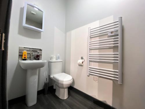 a white bathroom with a toilet and a sink at StayCrewe Apartments in Crewe