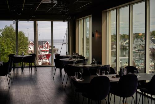 a restaurant with tables and chairs and large windows at The Tide - Hotel in Sørvågen