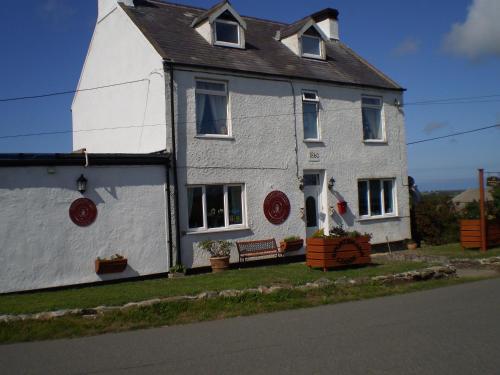 een wit huis met een rode krans erop bij Sportsmans Lodge Bed and Breakfast in Amlwch