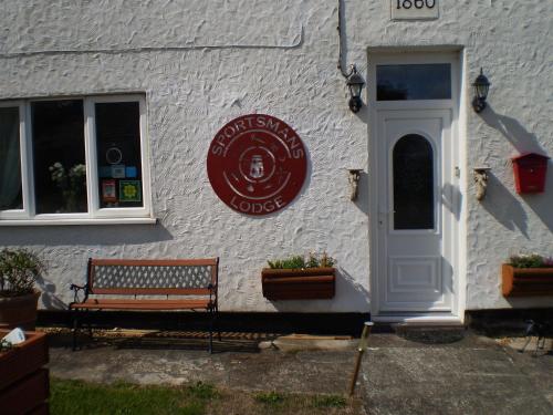 een gebouw met een bank en een bord erop bij Sportsmans Lodge Bed and Breakfast in Amlwch
